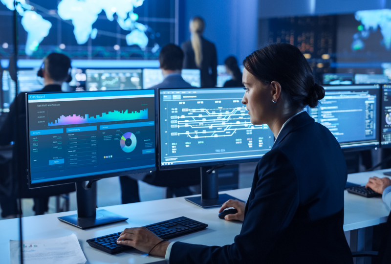 Woman analyzing data on computer screens.