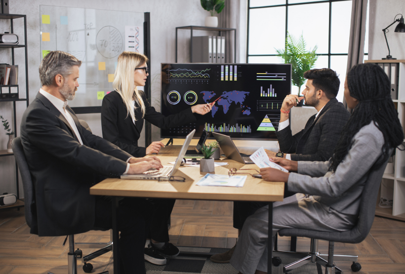 Business meeting with data presentation on screen.